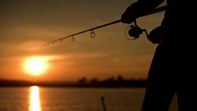 Fishermen are using fishing rods in the reservoir during Silhouette sunset.