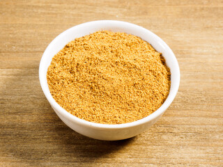 Spice masala powder in white bowl on brown wood background