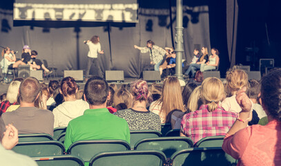 Rear view of audience at open air theatre in city center.
