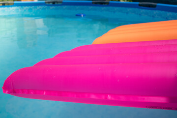 Colchonetas de color rosa y naranja en una piscina desmontable llena de agua