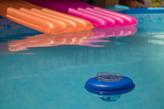 Piscina desmontable llena de agua con colchonetas y un dosificador de cloro