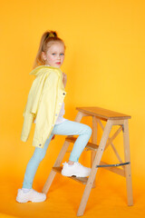 Beautiful portrat of young little girl in yellow studio and yellow bright clothes. Cute blonde child with plain healthy skin. Studio fashion model portrait. Blone girl with blue eyes