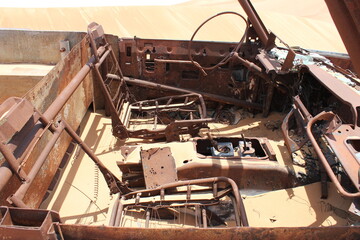 Burnt out wreckage of a SUV (4-wheel-drive) vehicle rusts away in hot and arid desert sand dunes terrain in Sharjah emirate in the United Arab Emirates.  