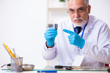 Old male expert criminologist working in the lab for evidence