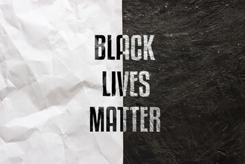 Black lives matter text on white crumpled paper and black grunge background. Anti-racist slogan....