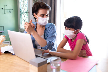 mother and daughter wearing surgical mask and working at home