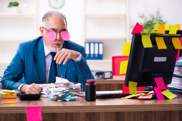 Old employee working in the office in conflicting priorities