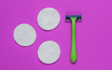 Beauty still life, minimalism. Plastic epilator razor with cotton circles on purple background. Women's accessories for beauty care. Top view