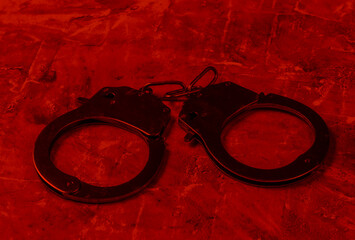 Steel handcuffs in red light. Crime, corruption concept
