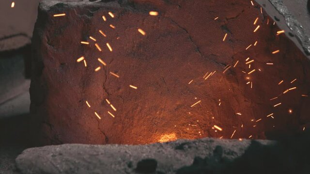 Hot metal knife piece taken out from furnace fire, sparks flying around