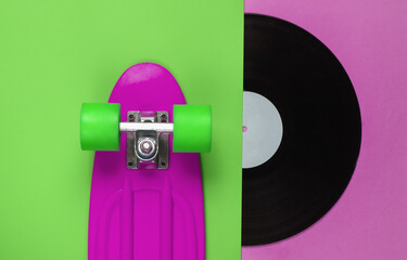 Retro style. Plastic mini cruiser board and vinyl record on colored background. Summer fun. Youth...