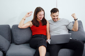 Obraz premium Smiling Caucasian Couple love relaxing and funny in online games with laptop in social media technology on sofa. Work from home and family lifestyle on holiday Concept.