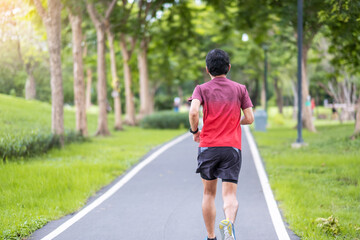 Fototapeta na wymiar Young adult male in sportswear running in the park outdoor, runner man jogging on the road, asian Athlete walking and exercise in morning. Fitness, wellness, healthy lifestyle and workout concepts