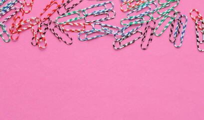 Lot of colored paper clips on pink background. Minimalistic office concept. Copy space