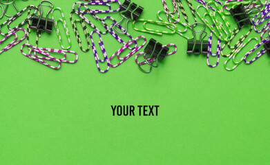 Lot of colored paper clips on green background. Minimalistic office concept. Copy space