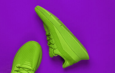 Stylish green sports shoes for running on purple background. Top view