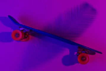 Plastic mini cruiser board on background with shadow from palm leaves. Neon gradient ligh. Top view