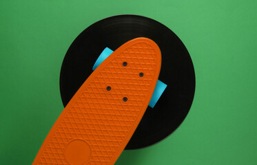 Cruiser board on vinyl record. Green background. Youth retro style concept. 80s. Top view