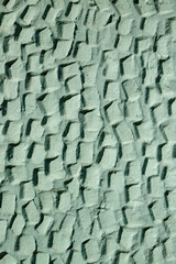 The texture of the plastered wall. Rough corrugated cement surface. Faded green color. Uneven angular pattern. Perfect for background and design.