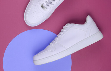 White sneakers on pink background with purple pastel circle. Youth hipster concept. Top view