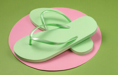 Flip flops on green background with pink pastel circle. Minimalistic vacation on the beach concept. Summer time