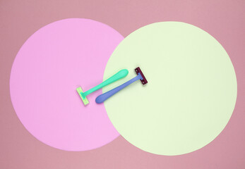 Colored plastic razors on background with pink yellow pastel circles. Minimalistic beauty still life