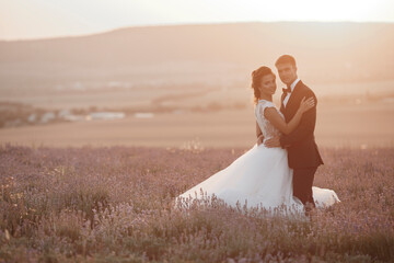 Fototapeta na wymiar Wedding couple in a lavender field at sunset, bride and groom