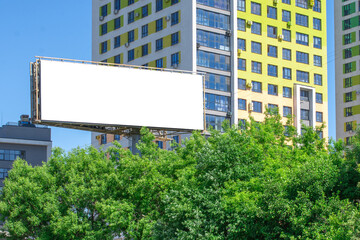 Blank billboard on the background of a building and green trees. Mockup