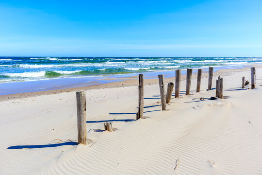Wooden breakwaters on beautiful white sand beach with blue sea near Kolobrzeg, Baltic Sea coast, Poland - Powered by Adobe