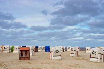 Verlassene Strandkörbe am Strand unter Wolkenhimmel