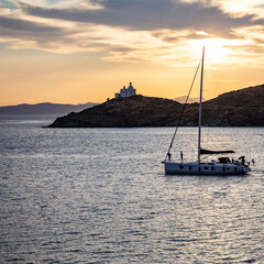 Fototapeta premium Sailing at sunset, Mediterranean sea. Lighthouse at Kea island, Greece.