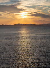 Fototapeta premium Sunrise, sunset clouds. Twilight, dusk cloudy sky over sea water, mountain silhouette