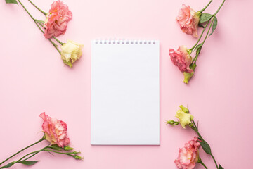 Notebook and pink flower bouquet on pastel background