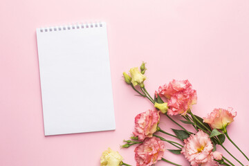 Notebook and pink flower bouquet on pastel background