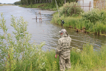 Naklejka premium Mann beim Angeln gefangen Fisch im Fluss Fischfang im Fluss
