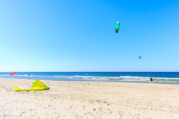 Kites flying on beautiful white sand beach with blue sea near Kolobrzeg, Baltic Sea coast, Poland