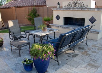 Patio furniture with an outdoor fireplace and potted plants

