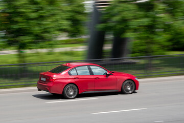 Fototapeta na wymiar Red car rides on the road. Motion blur photo