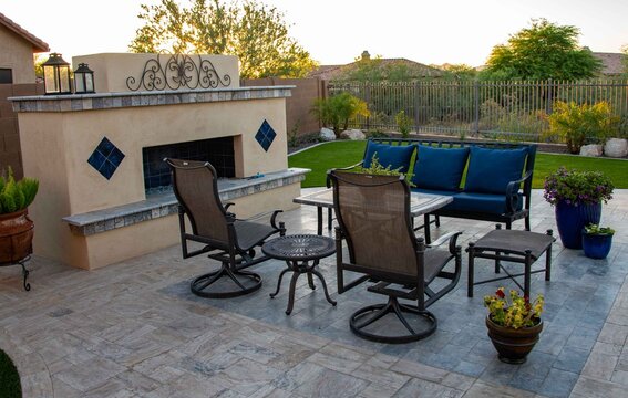 Patio Furniture With An Outdoor Fireplace And Potted Plants
