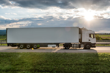 White truck is on highway - business, commercial, cargo transportation concept, beautiful sunset sky, clear and blank space - side view