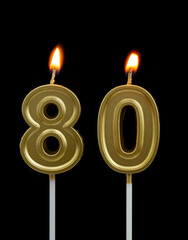 Burning golden birthday candles isolated on black background, number 80