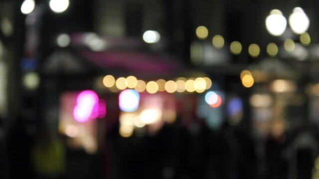 People walking in front of holiday lights with the Bokeh Effect blurring the image.