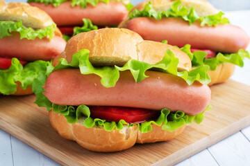 a few hot dogs on a wooden Board. Hot dog with lettuce tomato and sausage. Copy space.