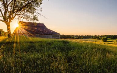 An old  abandoned barn under sunset with sunburst, sunstars © Yan