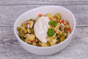 Traditional Russian salad with chicken in the white bowl