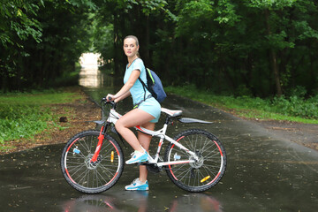 Fototapeta premium sport girl in sportswear stands by the bike in the park stopped and looks away