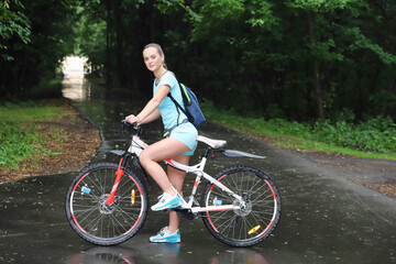 Fototapeta premium sport girl in sportswear stands by the bike in the park stopped and looks away