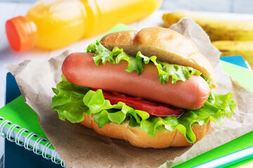 Hot dog with lettuce tomato and sausage. Notebooks and stationery. concept school Breakfast. Copy space.