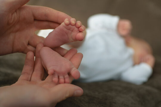 Father holding his newborn baby. Little foots of newborn girl in father's hands. Cute little children. Infant at the sofa. Image with selective focus.