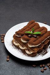 Classic tiramisu dessert on ceramic plate on concrete background